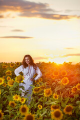 Fototapeta na wymiar Beautiful woman enjoying nature in the sunflower field at sunset. Traditional clothes. Attractive brunette woman with long and healthy hair.
