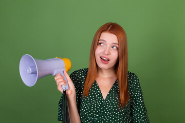Young red hair woman on green background with megaphone