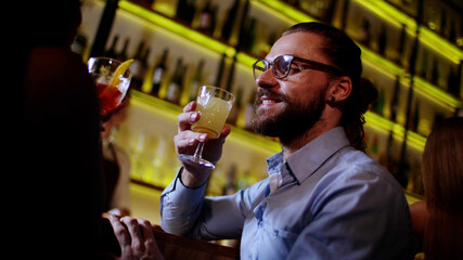 Cropped shot of hipster man in glasses holding cocktail glass and talk to woman in bar