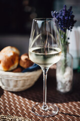 A glass of cold white wine and fresh pastries at a rustic style served table decorated with lavender. Serving lunch at winery.