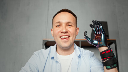 Experienced disabled company worker man waves artificial high tech hand prothesis