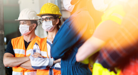 Factory workers of diverse ethnic backgrounds stand together and cross their arms. A group of...