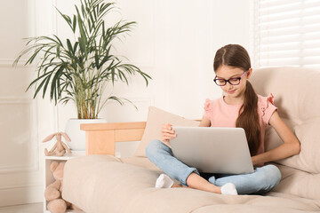 Girl with laptop on sofa at home