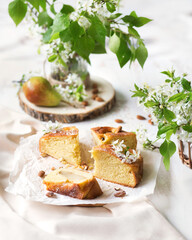 Pear cake. Summer dessert with fruit on a white table. A piece of cake on a ceramic plate. Fresh homemade cakes. Summer still life with cherry blossom
