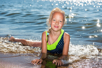 Little girl is laughing and swimming at sea on a sunny day