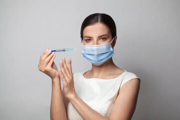 Portrait of perfect woman in protective face mask with syringe on white background