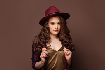 Nice brunette woman in fedora hat on brown background