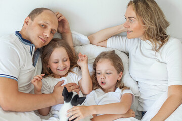 Happy family having fun in the bedroom while they lie on bed. Happy family with puppy dog pet