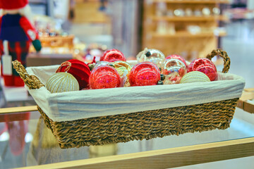 Multicolored balls for christmas trees in a wicker basket on a shop window