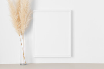 White frame mockup on the wall with a pampas decoration.
