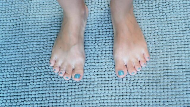 A Person's Feet Step on the Soft Blue Carpet in the Bathroom. Close-up of Legs and a Blue Fluffy Rug.
