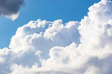 Naklejka na ściany i meble Large white cloud on a blue sky on a bright sunny summer day. Rural landscape.
