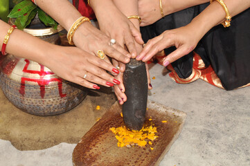 Group of Indian women holding a stone piece of mortar sil batta for making turmeric paste for wedding ceremony. Its a rituals of traditional Hindu marriage which is known as Haldi ceremony