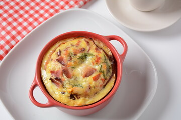 Omelette  with bacon, grated parmesan and greens in ceramic cocotte. Tasty breakfast