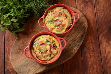 Omelette  with bacon, grated parmesan and greens in ceramic cocotte. Tasty breakfast