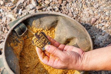 The fisherman's hand holds a fishing trough filled with bait.