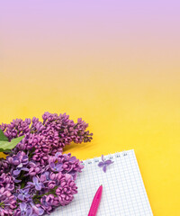 Spiral notebook and pen. Notepad with pen and flowers. Notebook lilacs on yellow background.