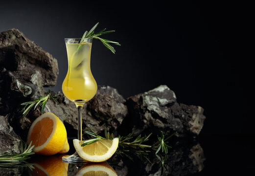 Traditional homemade lemon liqueur limoncello on the black background.