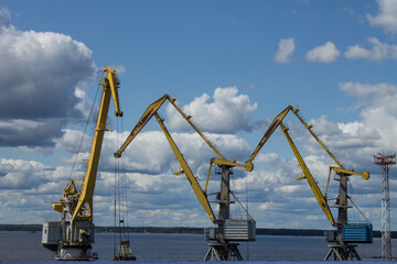 yellow port cranes on loading on the shore of the bay on a cloudy summer day in Vyborg Russia