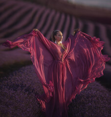 beautiful young girl in a pink dress walks in a lavender field