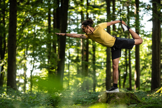 Junger Mann mit dunkler Haut macht Yoga Übung im Wald in der Natur