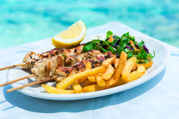 Chicken kebab on skewer in white plate with potatoes