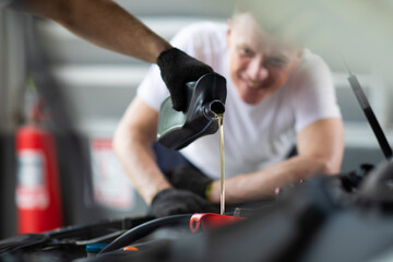 Pouring oil to car engine. Closue up male mechanic hand working  and service in Car Service station