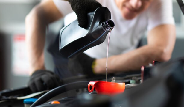 Pouring oil to car engine. Closue up male mechanic hand working  and service in Car Service station