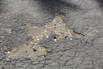 Textured surface of a muddy asphalt road with chips, cracks and scratches