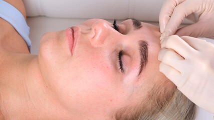 Fototapeta na wymiar Facial massage beauty treatment. Close up of a young womans face lying on back, getting face lifting massage, pinch and roll technique