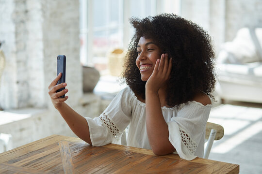 A happy young black african woman spending time at home using her cell phone and having fun communicating with her friends in social media. Receiving a love text message from her boyfriend.