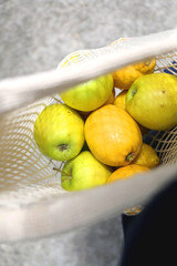 Crochet bag filled with apples and lemons. Top view, selective focus.