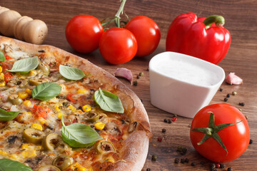 Vegetarian pizza and ingredients with spices on rustic wooden background, fast food