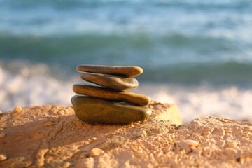 Stack of pebbles on a beach, illuminated by beautiful golden hour sunlight. Selective focus.