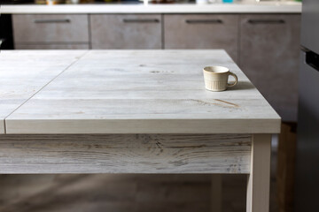 Small beige corrugated coffee empty cup eat on wooden table in beige kitchen interior