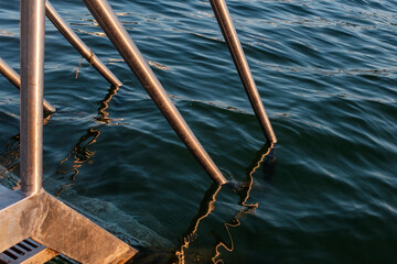 Fototapeta premium detail of swimming ladder in blue water at sundown