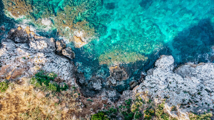 Obraz premium Turquoise emerald water of the Mediterranean Sea.Amazing aerial view of calm seaside.Rocky seashore top view.Holiday travel background copy space.Relax beach vacation luxury summer scene