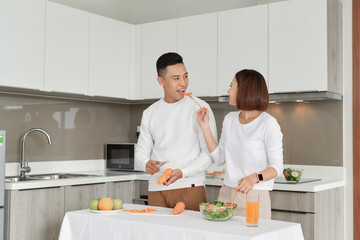 Happy couple standing in kitchen at home preparing together yummy dinner on first dating