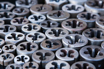 Many dies of different sizes for threading in metal, close-up.