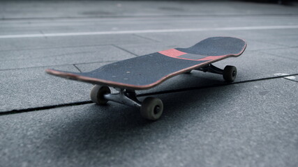 Black board with white wheels staying at city street. Skateboard for tricks.