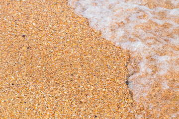 Fototapeta na wymiar small wave on the sandy shore close-up