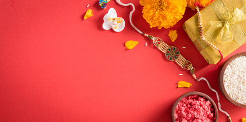 Raksha Bandhan, Indian festival with beautiful Rakhi and  Rice Grains on red background.  A...