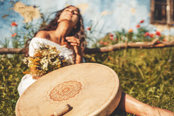 beautiful shamanic girl playing on shaman frame drum in the nature.