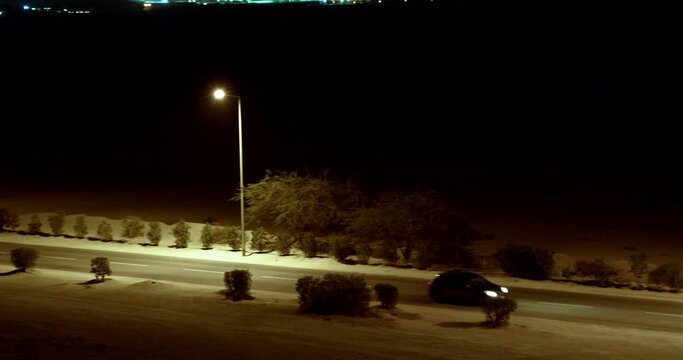 View from the hill of a car driving on a desert road at night
