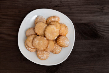 White plate with homemade shortbread cookies on wooden table. Top view. Baking for tea