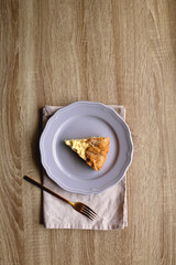 Slice of cheese and leek quiche on wooden table. Flat lay.