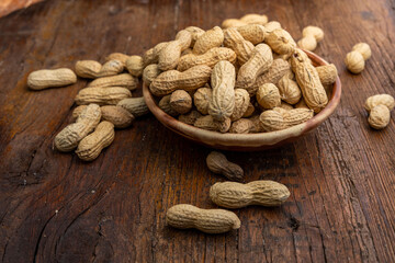 A lot of peanuts on a plate and  wooden background