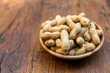 A lot of peanuts on a plate and  wooden background