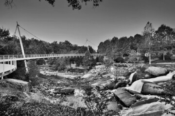 Black and white photo of steel suspension bridge and waterfall in park
