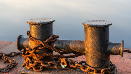 Mooring bollard on the mole with sunset river on the background. Space for text.
